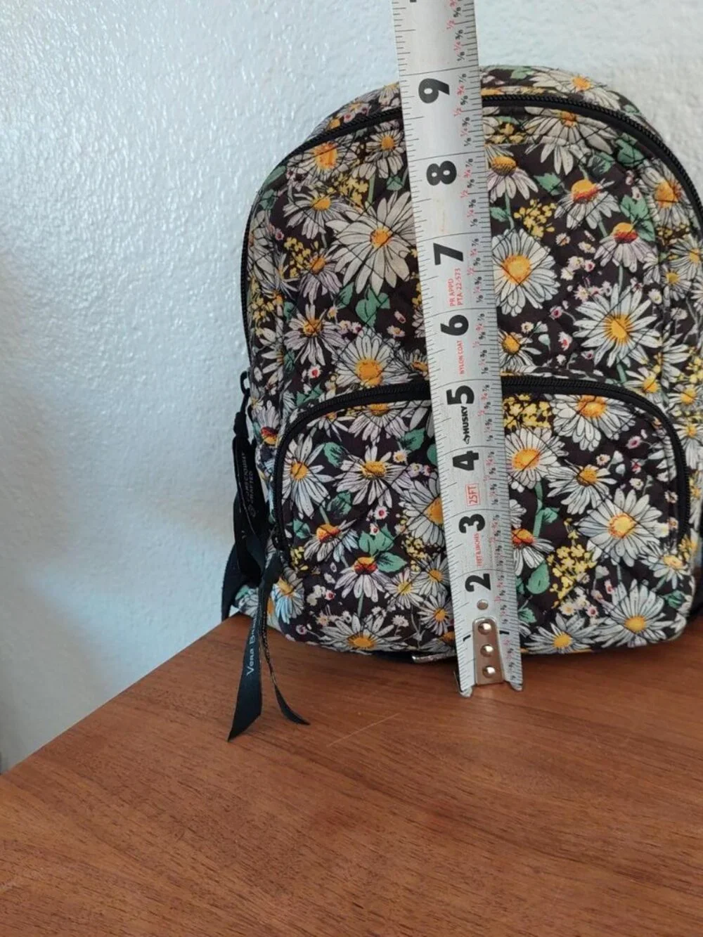 Vera Bradley Daisy Floral Backpack with white daisies and yellow centers on a da